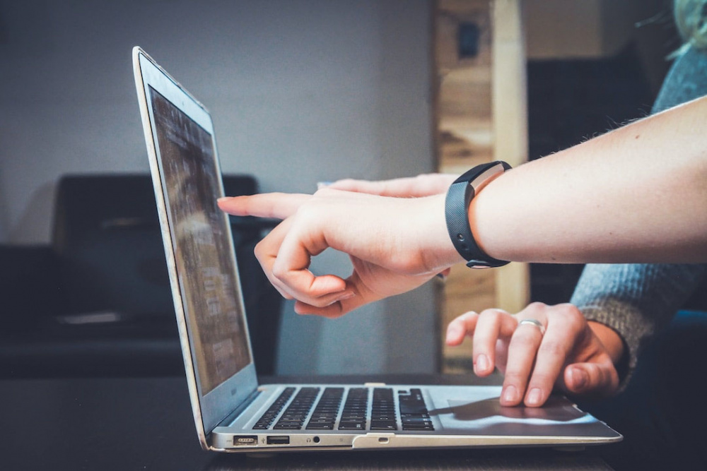 Two people pointing at a laptop screen discussing proposal automation.
